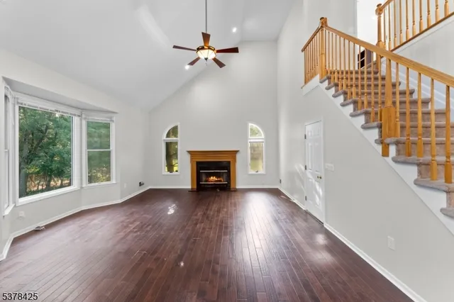 a view of an empty room with wooden floor fireplace and a window