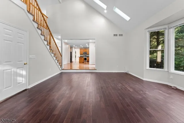 a view of an empty room with wooden floor and stairs