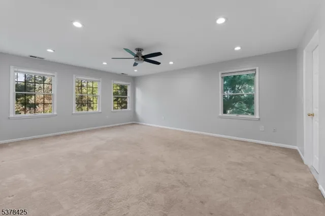 an empty room with windows and ceiling fan