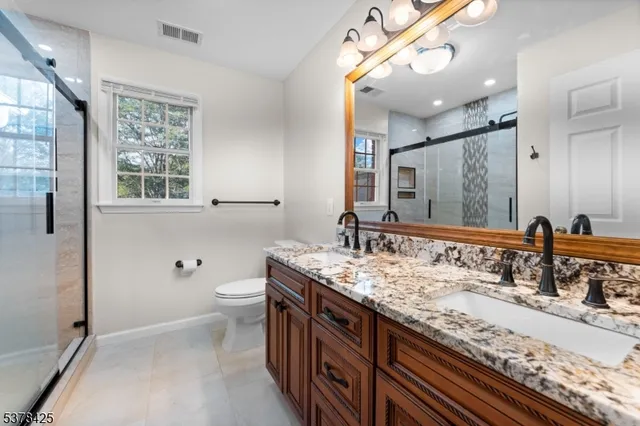 a bathroom with a granite countertop double vanity sink and a mirror