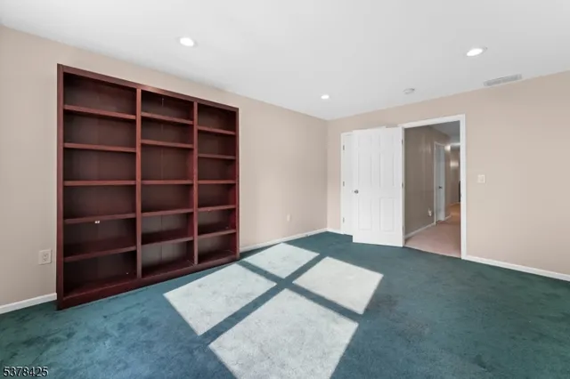 a view of an empty room with wooden floor and closet