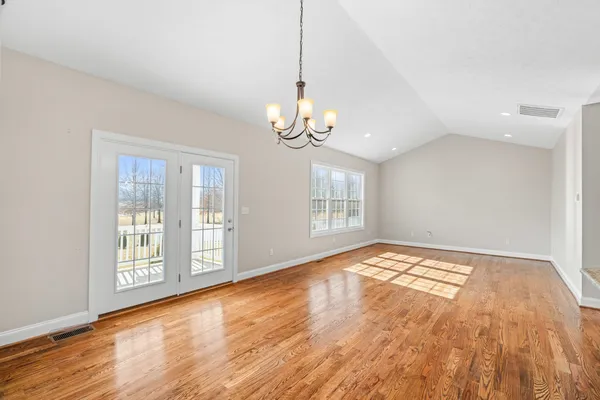 a view of an empty room with window and wooden floor