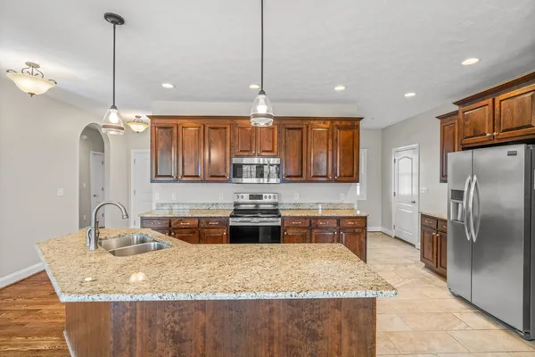 a kitchen with stainless steel appliances granite countertop a sink a stove and a wooden floor