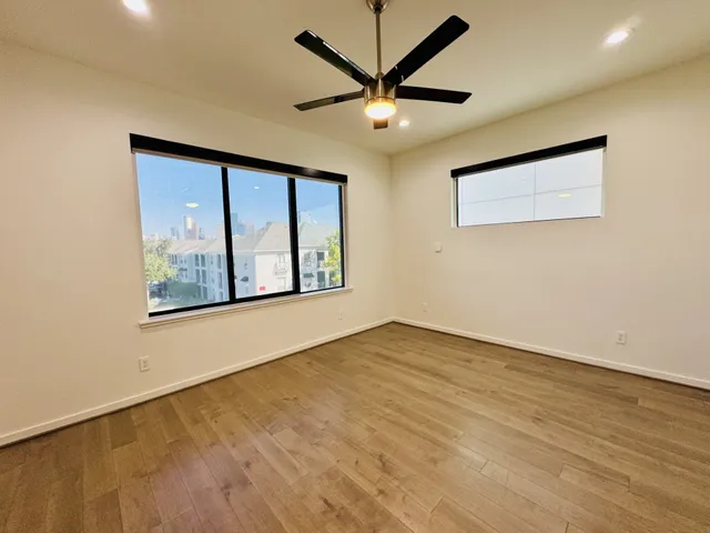 an empty room with wooden floor and windows
