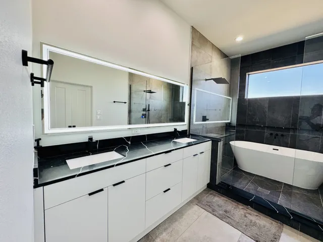 a spacious bathroom with a granite countertop double vanity sink a mirror and bathtub