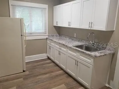 a kitchen with granite countertop white cabinets and white appliances