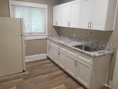 318 East Tarpon Avenue, Unit 5 Tarpon Springs, FL 34689 - Photo 7 of 16 a kitchen with granite countertop white cabinets and white appliances