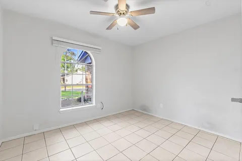 an empty room with windows and fan