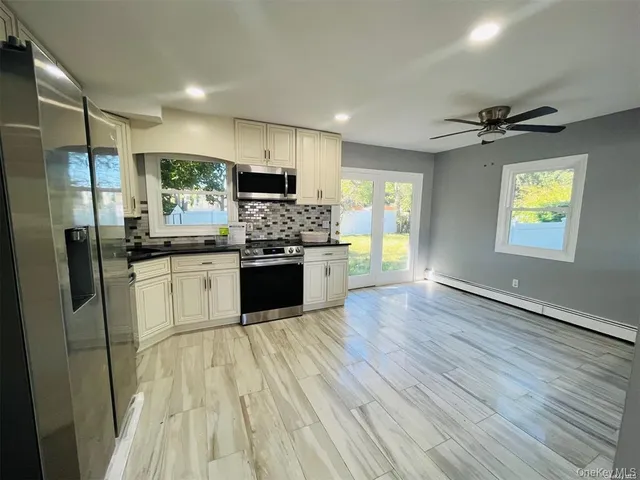 a kitchen with stainless steel appliances granite countertop a refrigerator a sink dishwasher a stove and white countertops with wooden floor