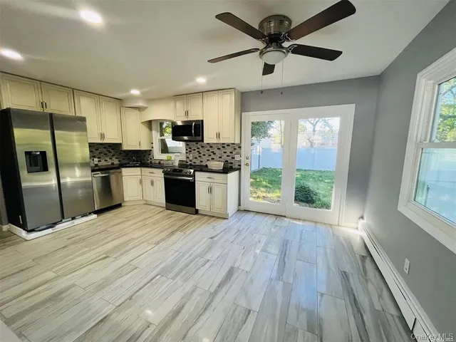 a large kitchen with stainless steel appliances a large counter top a sink a refrigerator and a window