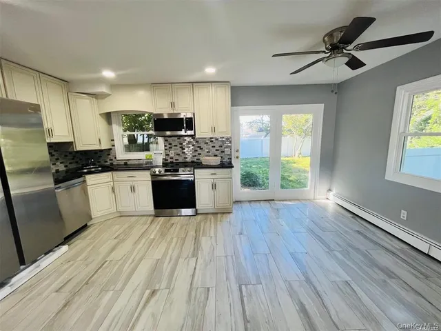 a kitchen with stainless steel appliances a stove a sink dishwasher a refrigerator with white cabinets and wooden floor