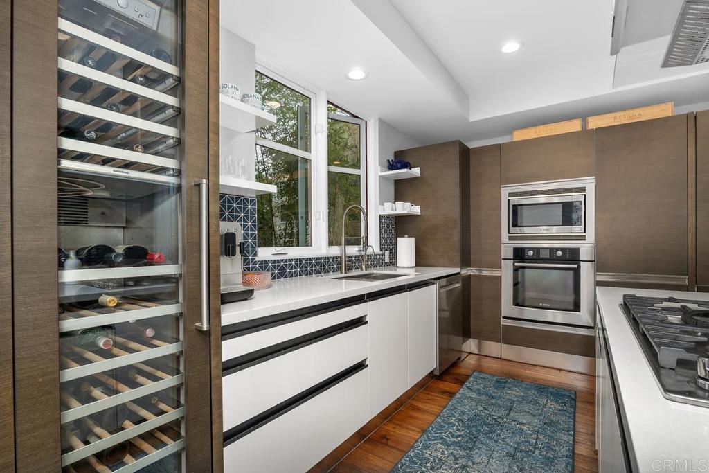 215 2nd Street, Unit 101 Encinitas, CA 92024 - Photo 17 of 47 a kitchen with stainless steel appliances kitchen island granite countertop a stove and a refrigerator