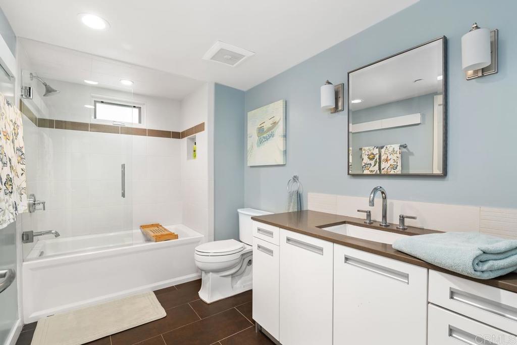 215 2nd Street, Unit 101 Encinitas, CA 92024 - Photo 37 of 47 a bathroom with a granite countertop sink a toilet a mirror a bathtub and shower