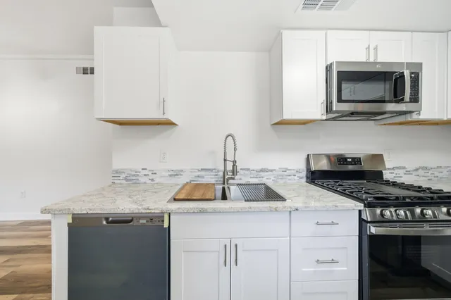 a kitchen with stainless steel appliances granite countertop a sink stove and microwave