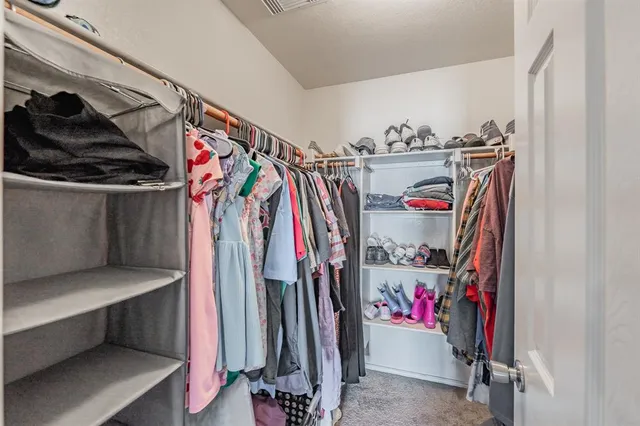 a view of walk in closet with clothes and shoes