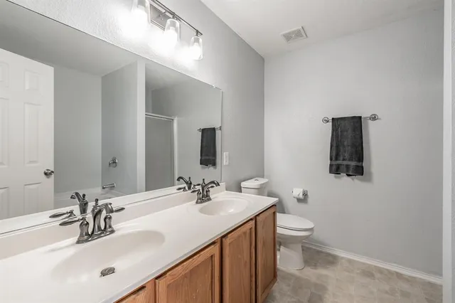 a bathroom with a double vanity sink toilet and mirror