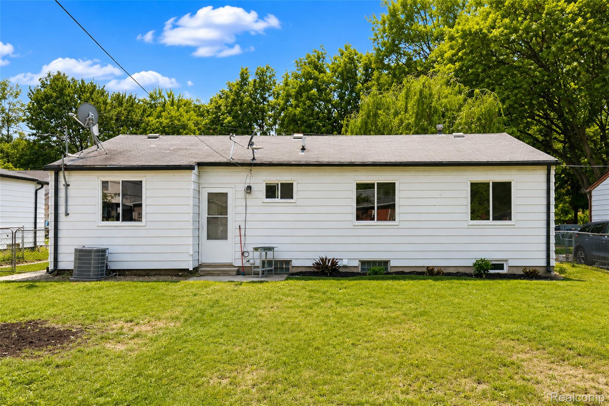 201 Cardwell Street Inkster, MI 48141 - Photo 7 of 41 Expansive rear yard featuring green lawn, white vinyl siding, multiple windows, and a rear entry door