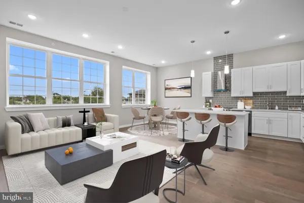a living room with couches a coffee table and kitchen view with wooden floor