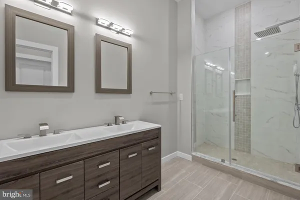 a bathroom with a double vanity sink mirror and shower