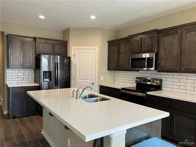 a kitchen with kitchen island a sink appliances and cabinets