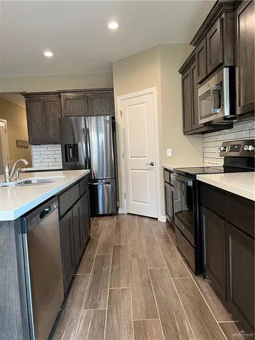 a kitchen with stainless steel appliances a sink cabinets and wooden floor