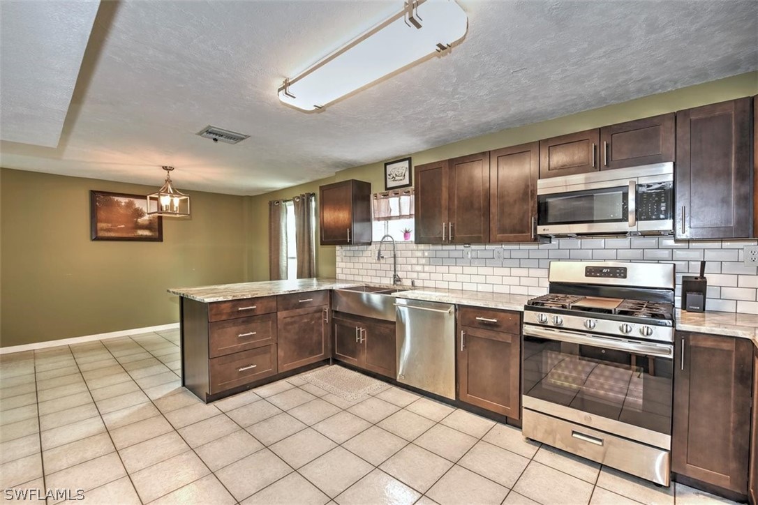 5320 Obannon Road Fort Myers, FL 33905 - Photo 7 of 28 a kitchen with stainless steel appliances granite countertop a stove microwave and cabinets
