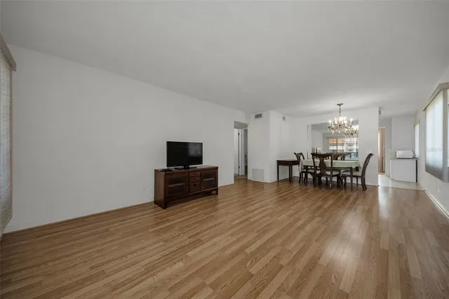 a dining room with furniture wooden floor a potted plant a painting and a chandelier