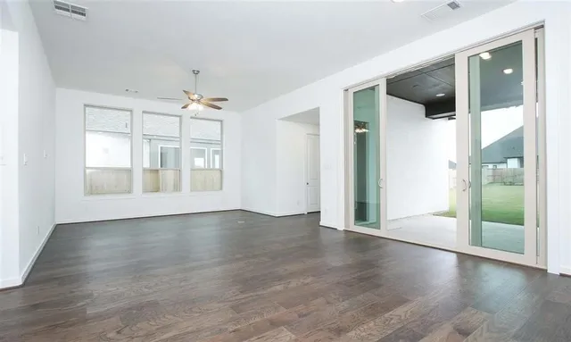 an empty room with wooden floor and windows