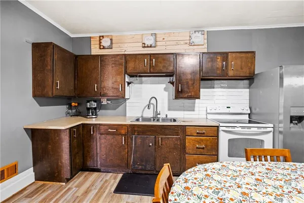 a kitchen with stainless steel appliances a sink a stove a refrigerator cabinets and a dining table