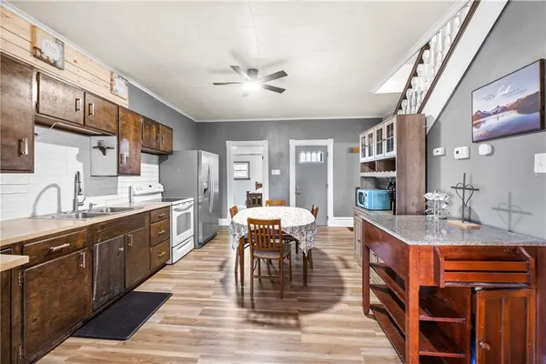 a kitchen with stainless steel appliances granite countertop a sink dishwasher stove refrigerator dining table and chairs