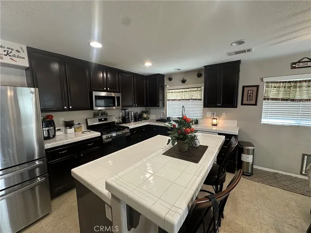 a kitchen with a refrigerator a sink dishwasher a dining table and chairs with wooden floor