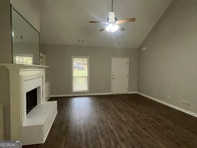 an empty room with wooden floor fireplace and windows