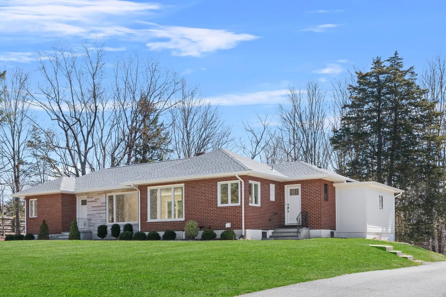 a front view of a house with a garden and trees