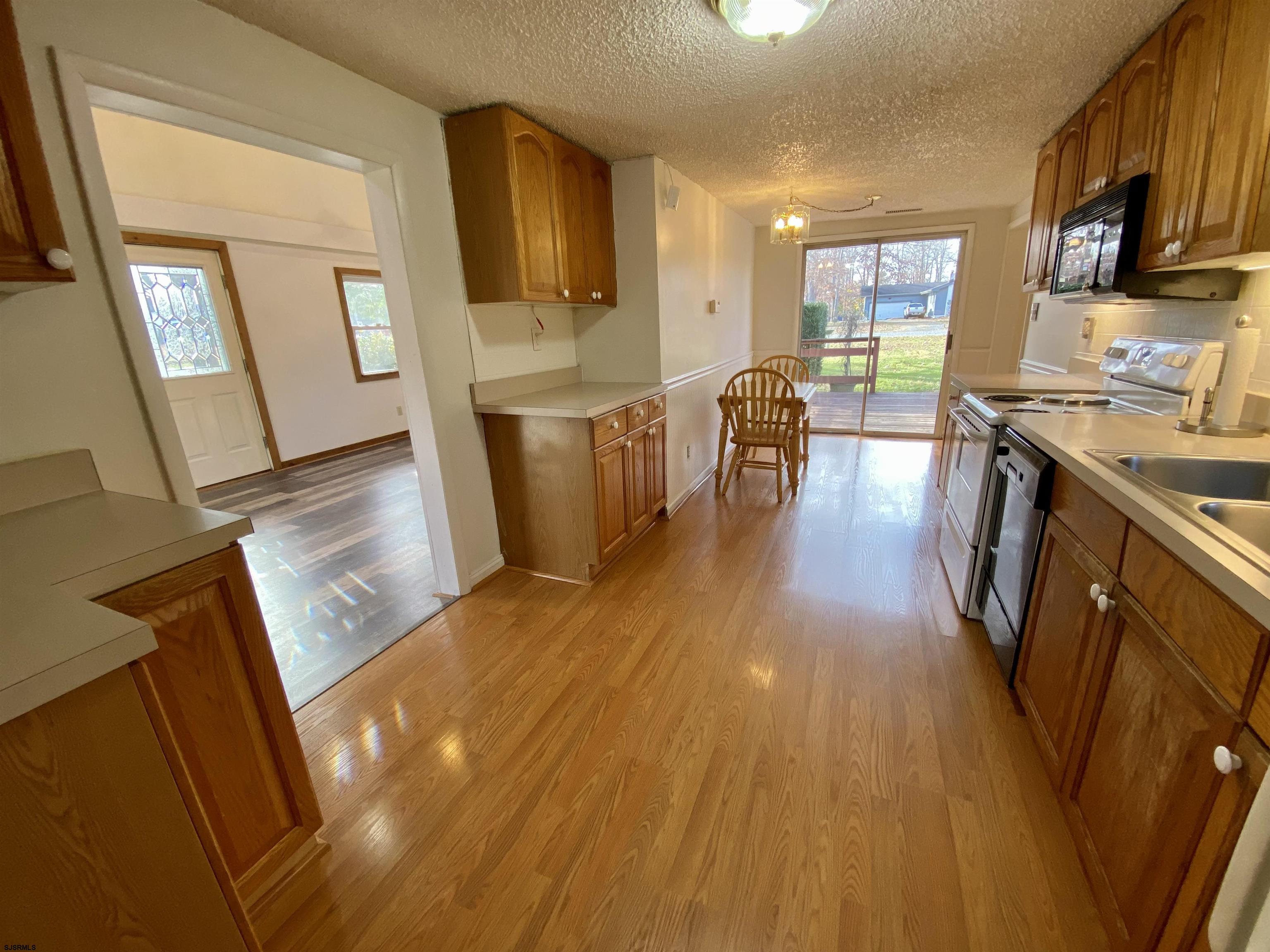 201 Broad Street Milmay, NJ 08340 - Photo 7 of 23 a open kitchen with cabinets a sink and wooden floor