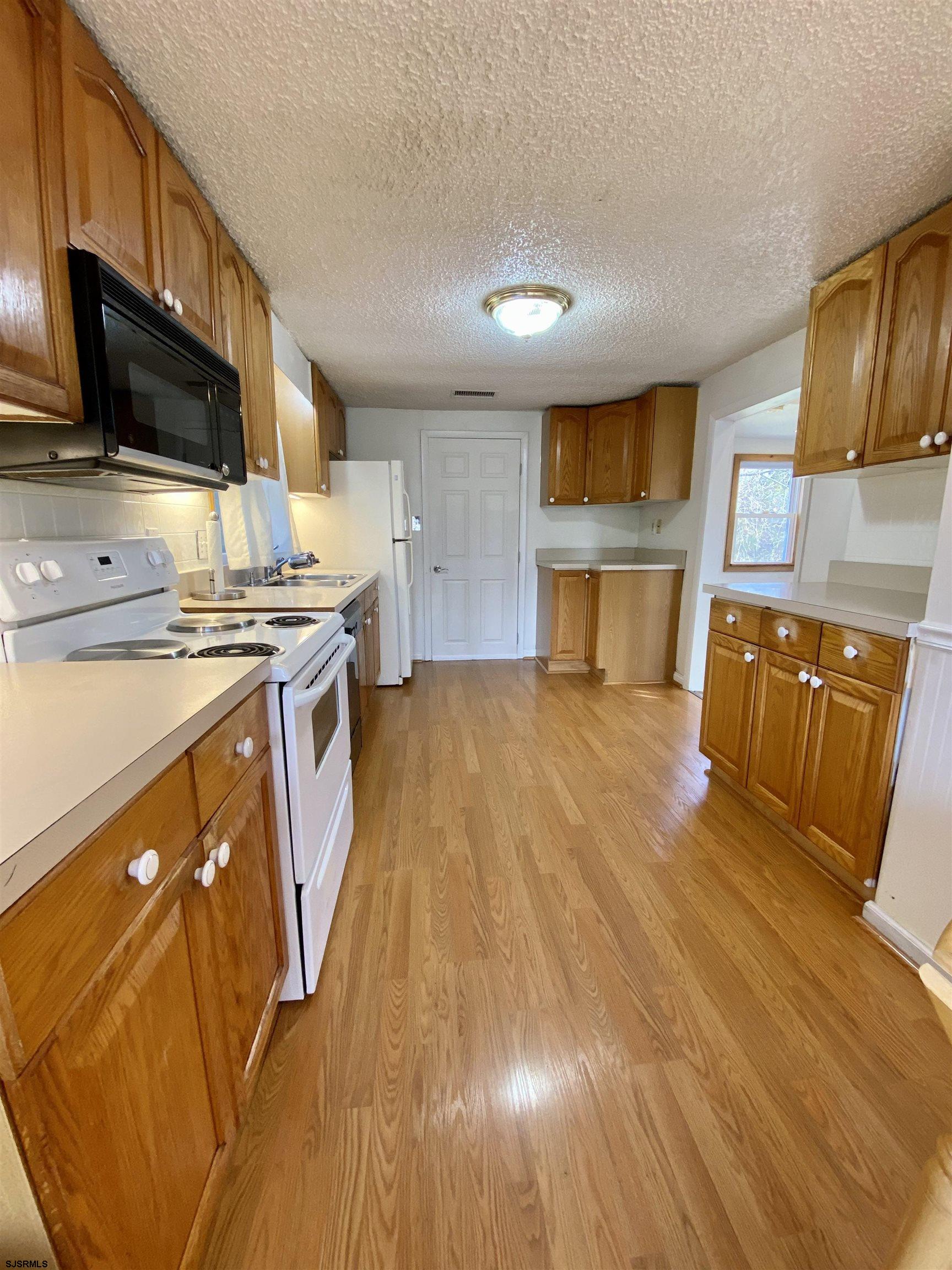 201 Broad Street Milmay, NJ 08340 - Photo 8 of 23 a kitchen with stainless steel appliances a stove a sink cabinets and a wooden floor
