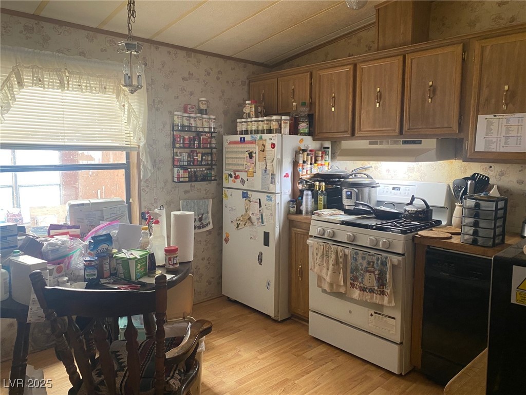18 Pine Street Ruth, NV 89319 - Photo 4 of 12 Kitchen featuring white appliances, under cabinet range hood, wallpapered walls, brown cabinets, and light wood-type flooring