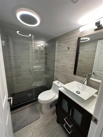 a bathroom with a sink a toilet a mirror and shower