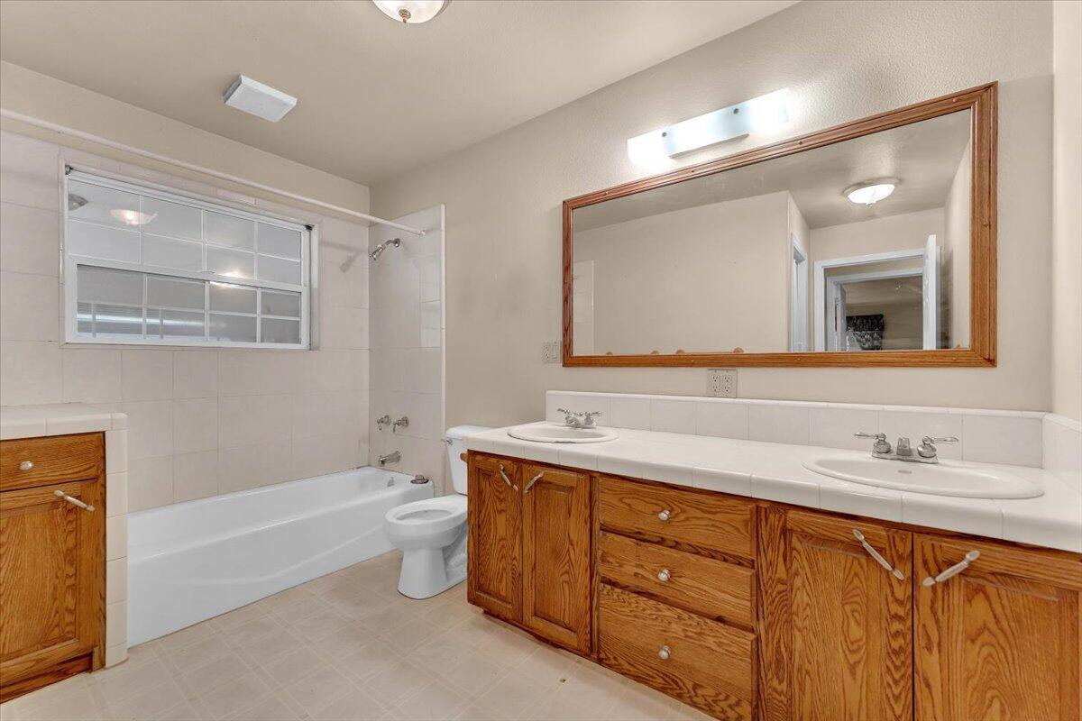 30153 Frisby Road Oak Run, CA 96069 - Photo 29 of 56 a bathroom with a double vanity sink a toilet a mirror and bathtub
