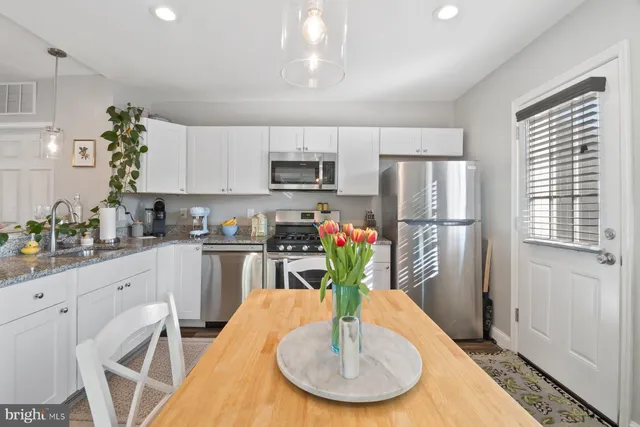 a kitchen with stainless steel appliances granite countertop a refrigerator a stove a sink dishwasher and white cabinets with wooden floor