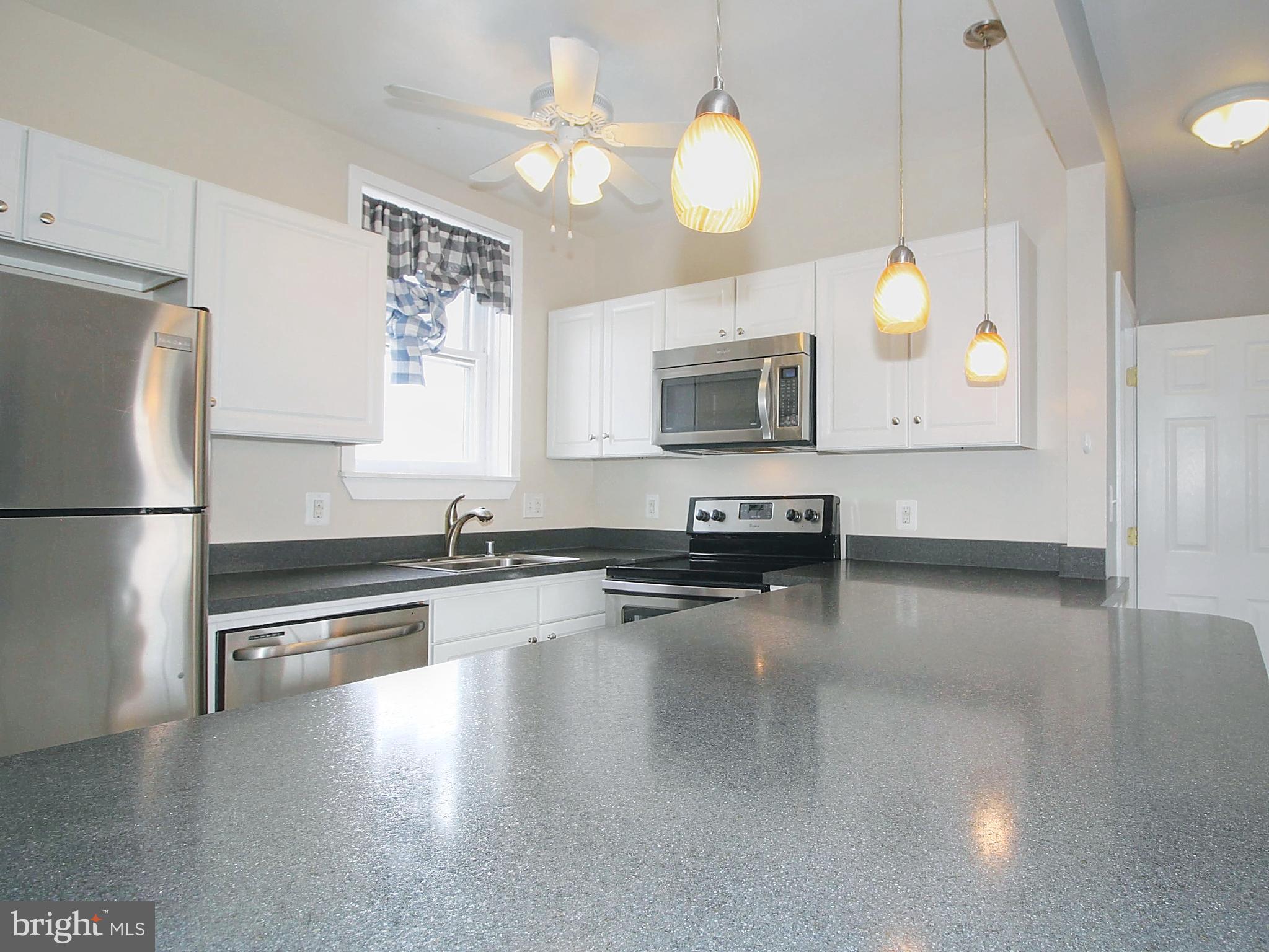 22 North Market Street, Unit 3 Frederick, MD 21701 - Photo 15 of 16 a kitchen with granite countertop a stove a oven a sink dishwasher and a microwave with wooden floor