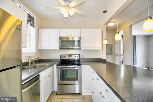 a kitchen with stainless steel appliances granite countertop a sink a stove top oven a counter space and cabinets