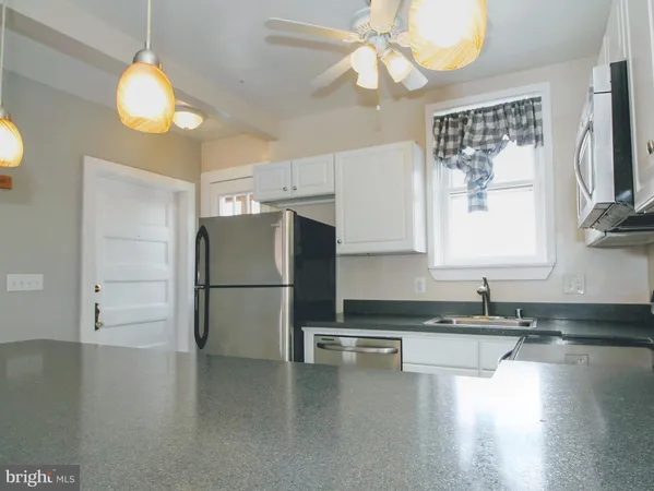 a kitchen with granite countertop a refrigerator a stove a sink dishwasher and white cabinets with wooden floor