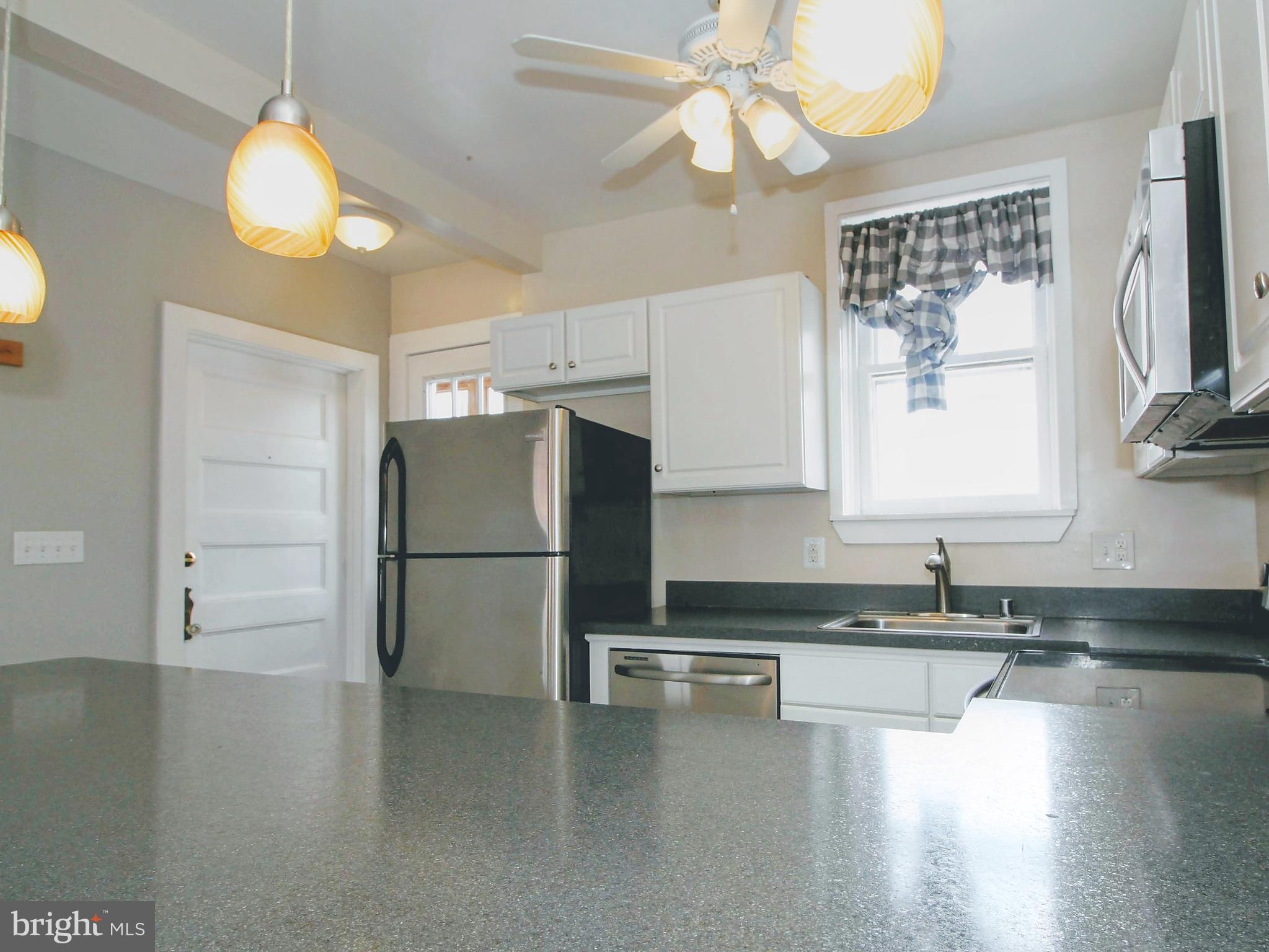 22 North Market Street, Unit 3 Frederick, MD 21701 - Photo 5 of 16 a kitchen with granite countertop a refrigerator a stove a sink dishwasher and white cabinets with wooden floor
