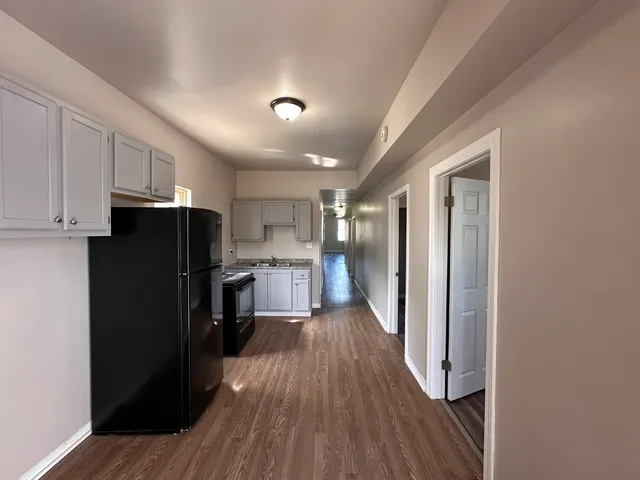 a view of a kitchen with refrigerator and wooden floor