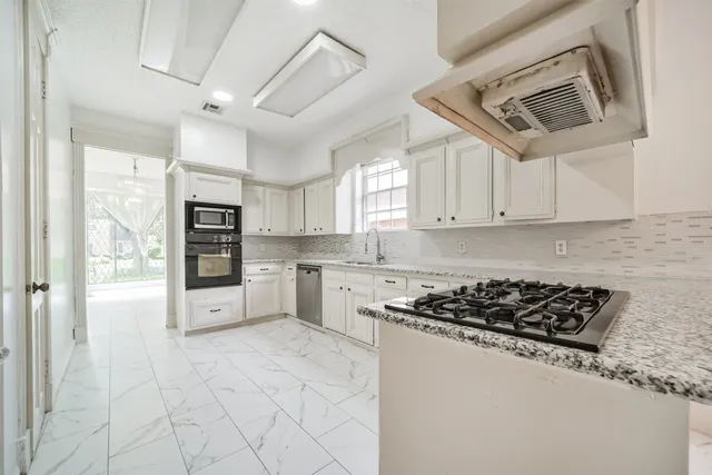 a kitchen with stainless steel appliances granite countertop a stove a sink and a refrigerator