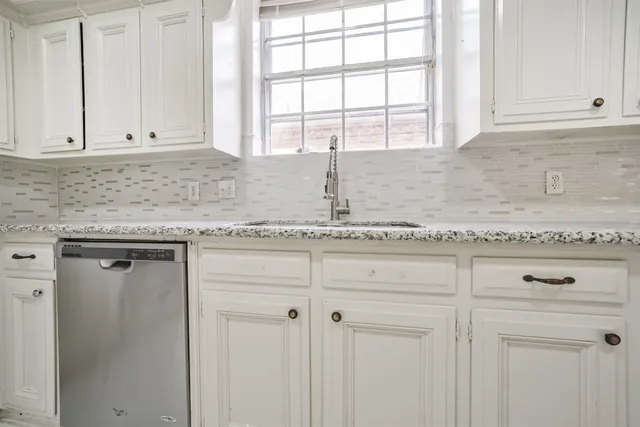 a kitchen with granite countertop white cabinets and a window
