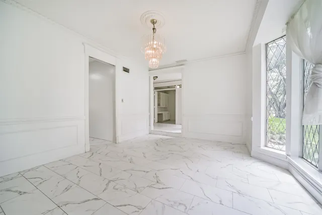 a view of an empty room with window and chandelier