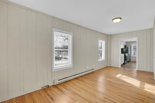 a view of an empty room with wooden floor and a window