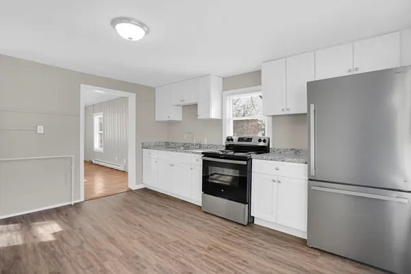 a kitchen with granite countertop a refrigerator stove and wooden floor
