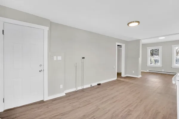 a view of an empty room with wooden floor and a window